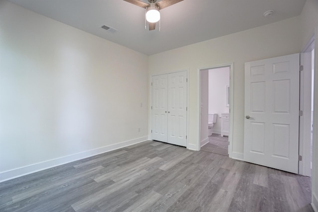 unfurnished bedroom with baseboards, visible vents, wood finished floors, and ensuite bathroom