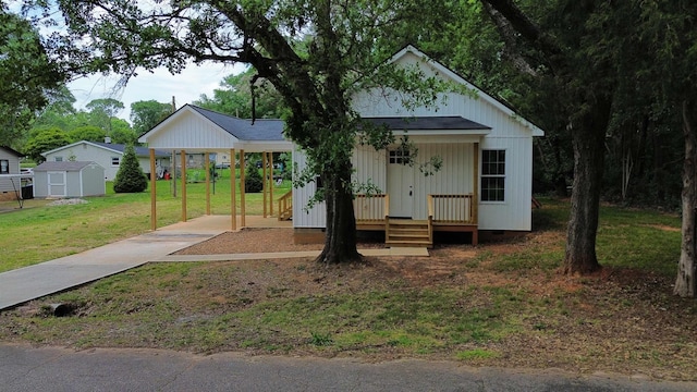 view of front facade with a storage shed, a porch, a front yard, an outbuilding, and driveway
