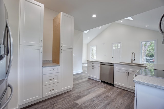 kitchen featuring white cabinetry, a sink, light wood finished floors, appliances with stainless steel finishes, and a wealth of natural light