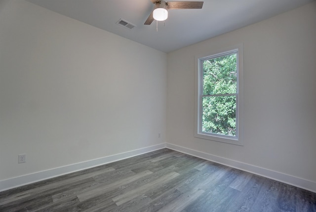 empty room featuring dark wood-style flooring, baseboards, visible vents, and a ceiling fan