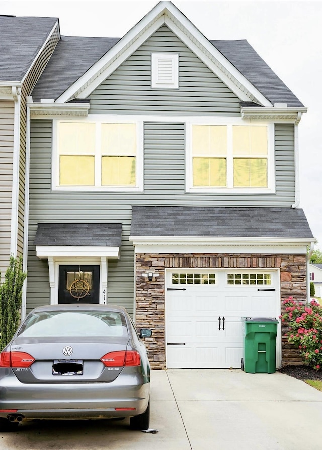 craftsman inspired home with roof with shingles, an attached garage, driveway, and stone siding
