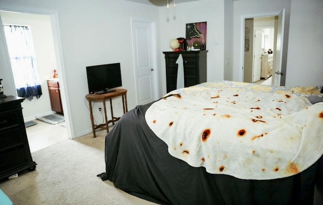 bedroom featuring baseboards, ensuite bathroom, and light colored carpet