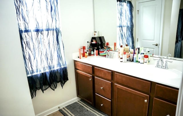 bathroom with a sink, baseboards, and double vanity