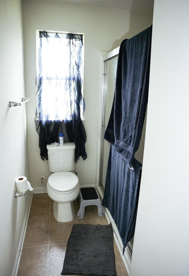 full bathroom with tile patterned flooring, baseboards, a stall shower, and toilet