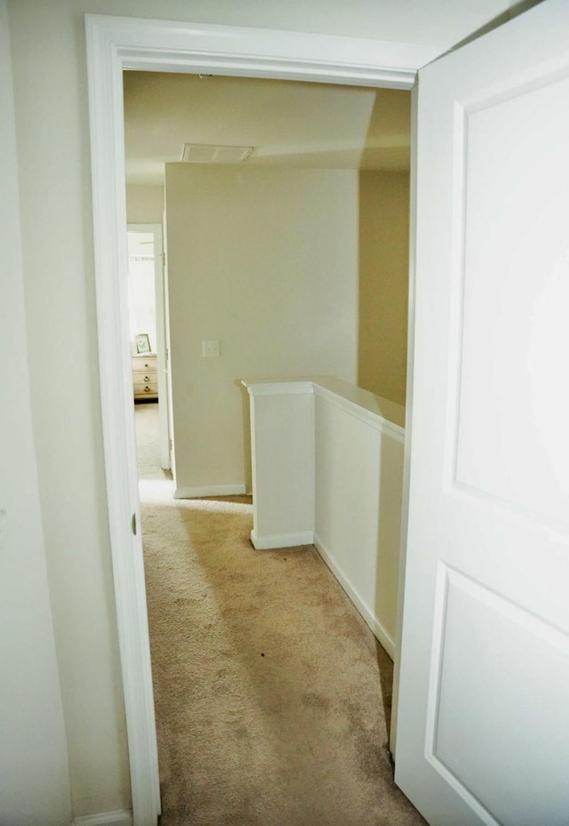 hallway featuring visible vents, an upstairs landing, and carpet