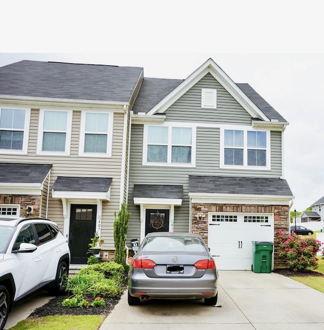 multi unit property featuring concrete driveway, stone siding, and a garage