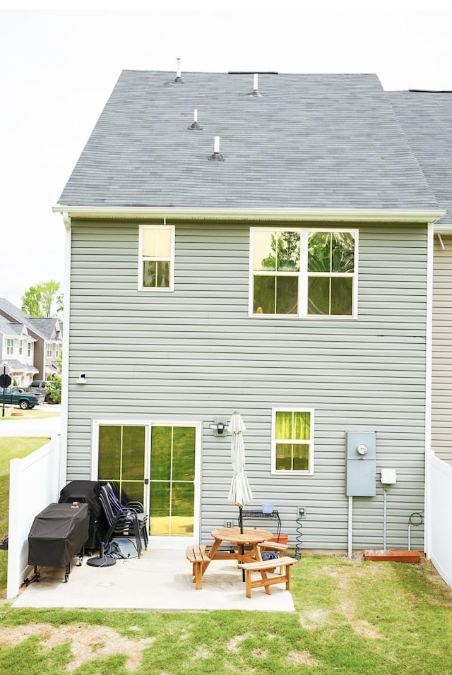 back of house featuring a lawn, a shingled roof, a patio area, and fence