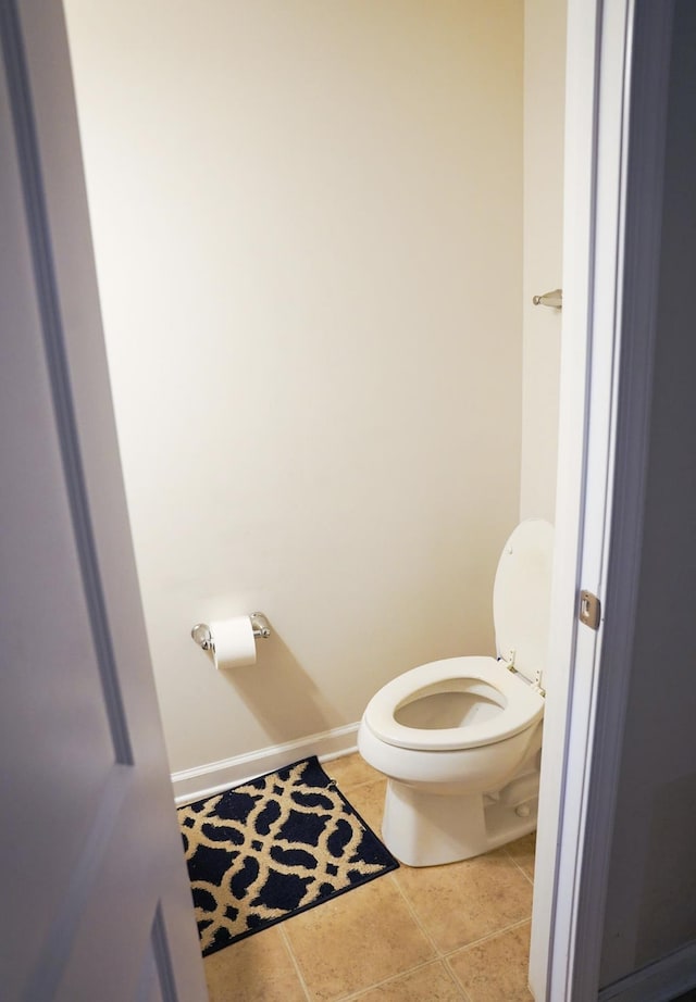 bathroom with baseboards, tile patterned flooring, and toilet