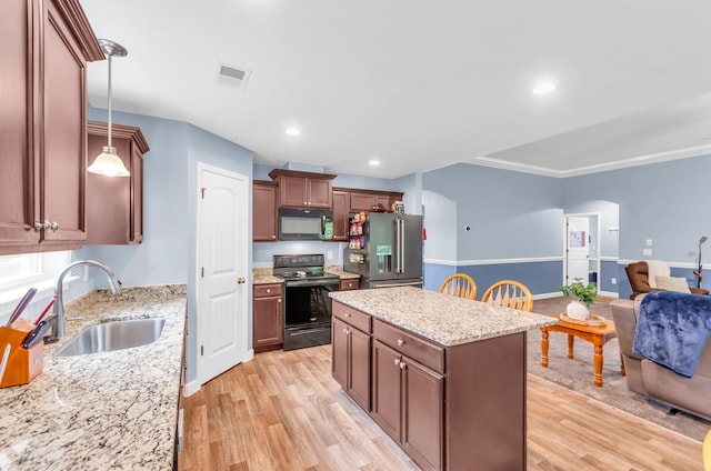 kitchen with arched walkways, light wood finished floors, a sink, and black appliances