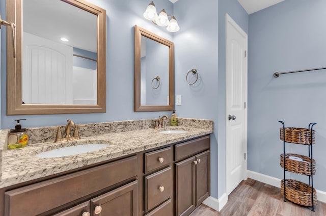 bathroom featuring double vanity, a sink, baseboards, and wood finished floors