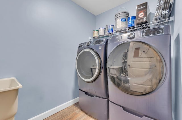 laundry area with baseboards, laundry area, washing machine and dryer, and light wood-style flooring