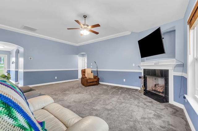 living area featuring a tiled fireplace, arched walkways, ceiling fan, and visible vents