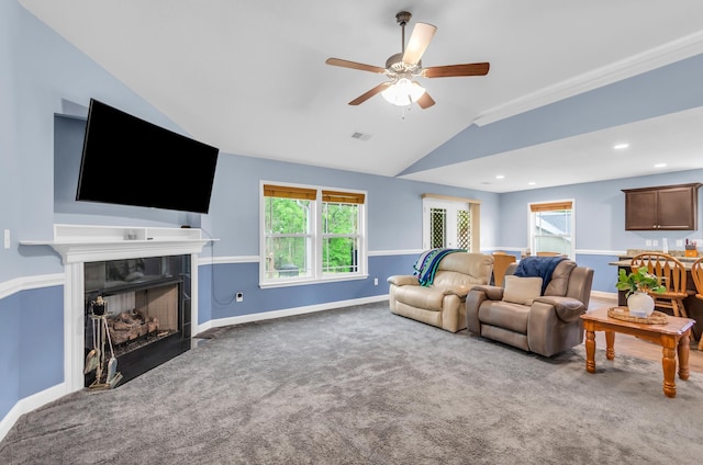 living area with lofted ceiling, baseboards, ceiling fan, a tile fireplace, and carpet