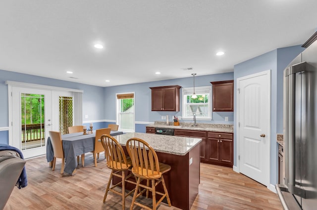 kitchen with a sink, light wood finished floors, black dishwasher, and a healthy amount of sunlight