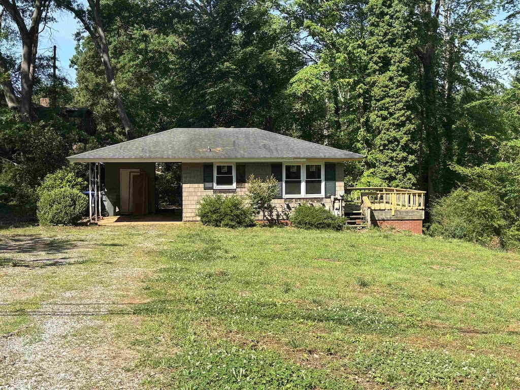 ranch-style home with a front lawn, a wooden deck, and a carport