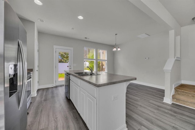 kitchen featuring dark wood-style flooring, appliances with stainless steel finishes, a center island with sink, and a sink