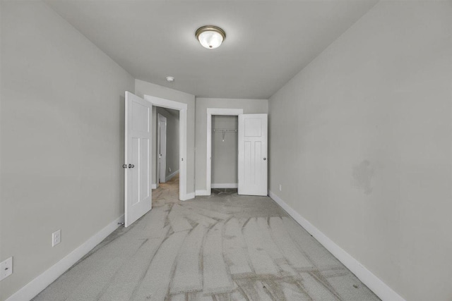 unfurnished bedroom featuring carpet floors, baseboards, and a closet