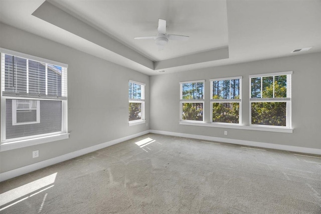 carpeted spare room with baseboards, ceiling fan, and a tray ceiling