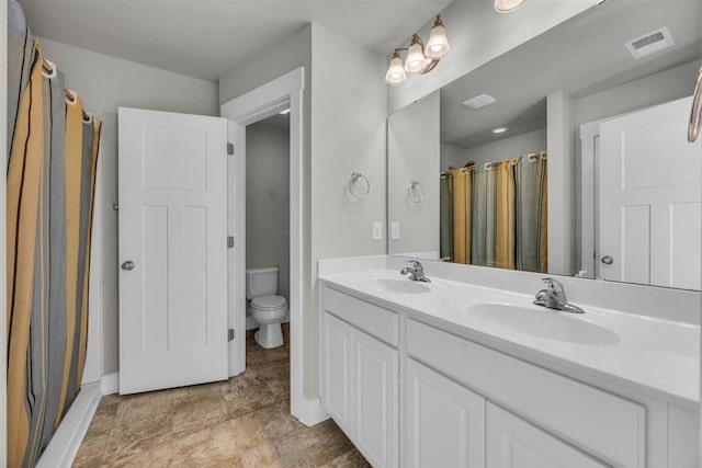bathroom with a sink, baseboards, toilet, and visible vents