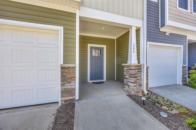 view of exterior entry featuring covered porch, an attached garage, and stone siding