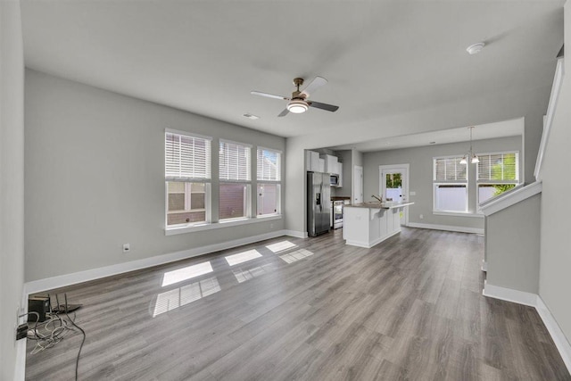 unfurnished living room with baseboards, ceiling fan, and dark wood-style flooring