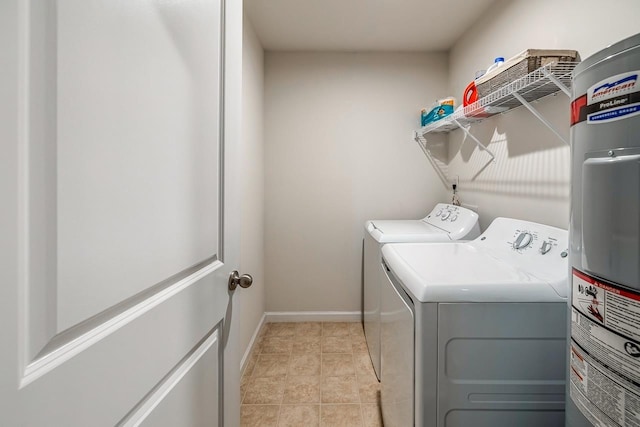 clothes washing area featuring washer and dryer, laundry area, baseboards, and water heater