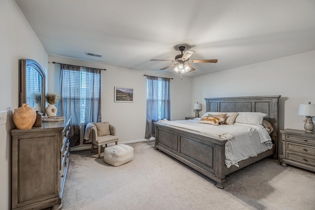 bedroom featuring ceiling fan, visible vents, light carpet, and multiple windows
