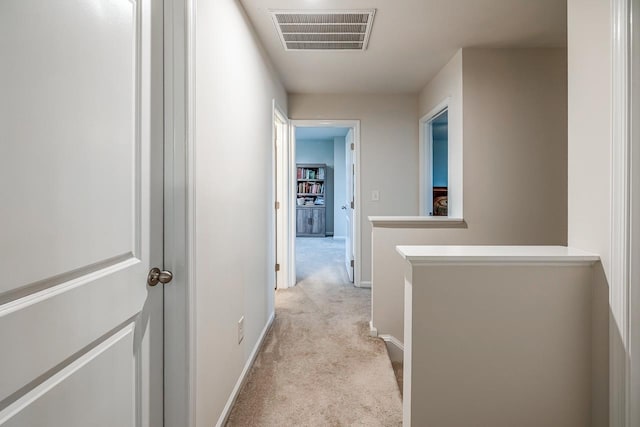 hallway with baseboards, light carpet, and visible vents