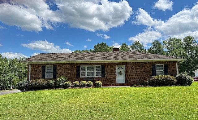 ranch-style home with a chimney, a front lawn, and brick siding