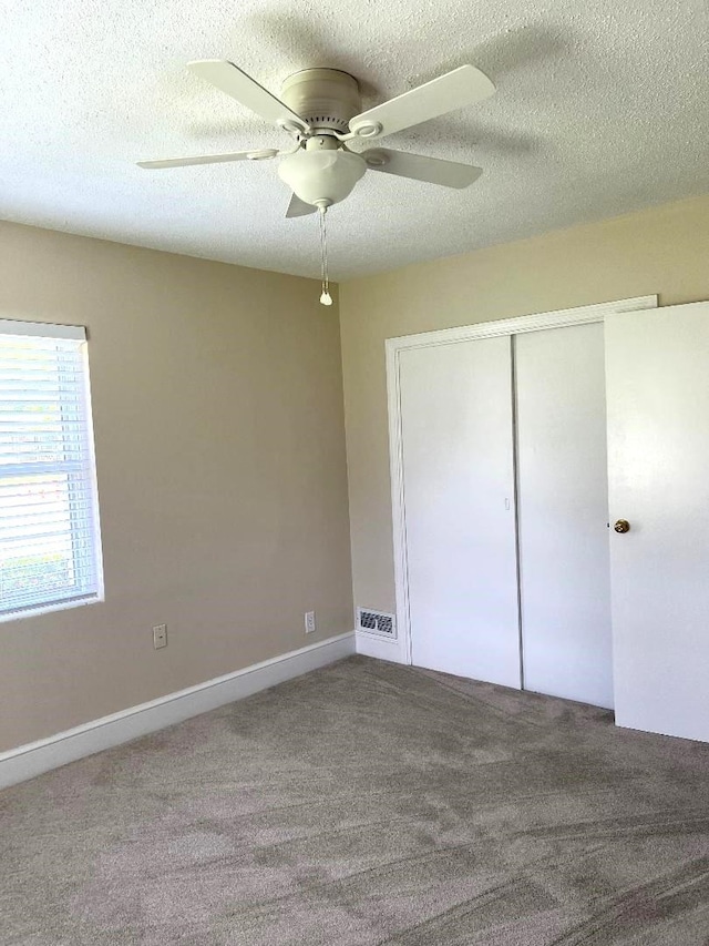 unfurnished bedroom with a closet, a textured ceiling, carpet, and ceiling fan