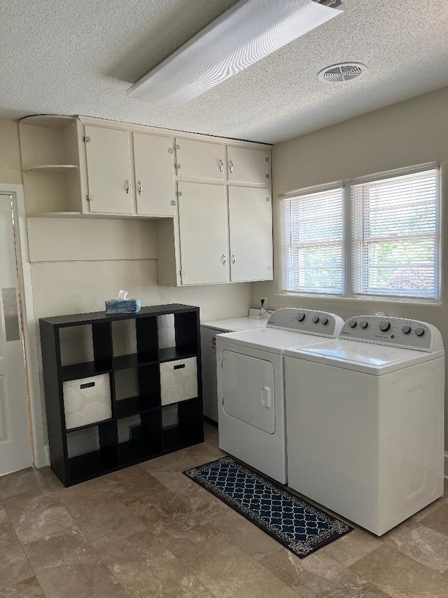 laundry area featuring visible vents, a textured ceiling, cabinet space, and independent washer and dryer
