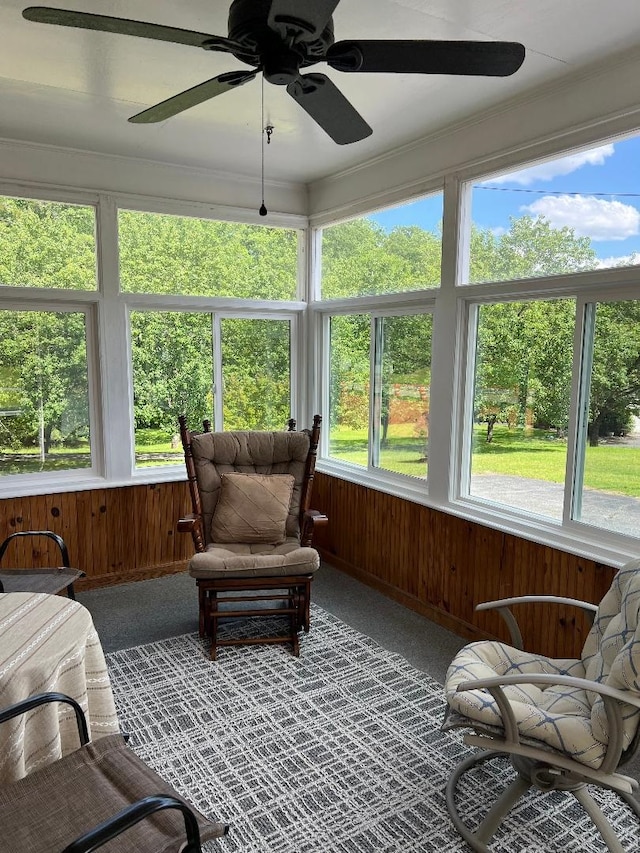 sunroom / solarium featuring carpet flooring, crown molding, and wood walls
