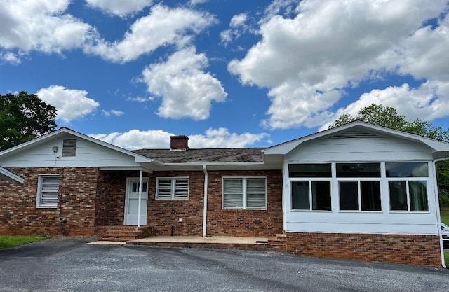 single story home with brick siding and a chimney