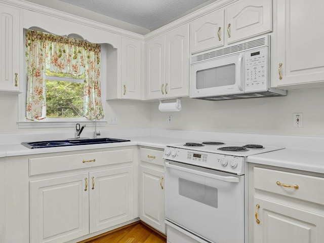 kitchen with a sink, white appliances, white cabinetry, and light countertops
