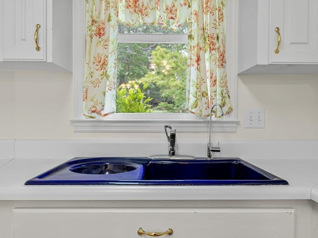 room details featuring light countertops, white cabinets, and a sink