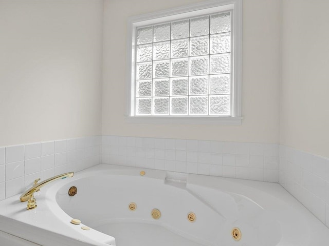 full bathroom with a whirlpool tub and a healthy amount of sunlight