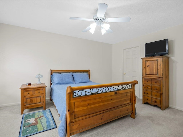 carpeted bedroom featuring baseboards and a ceiling fan