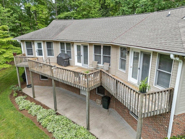 rear view of house featuring a patio area, roof with shingles, and a deck