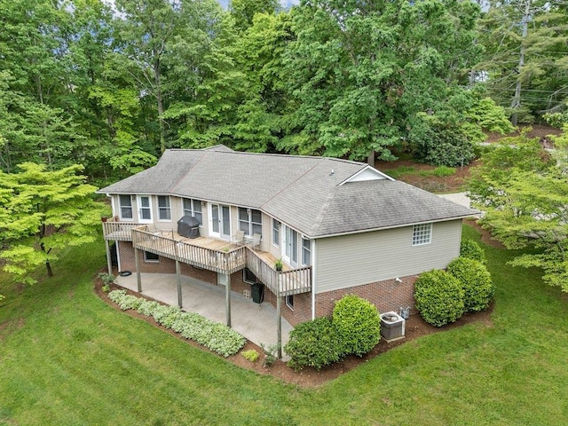 rear view of house with a lawn, a patio, a shingled roof, and a wooden deck