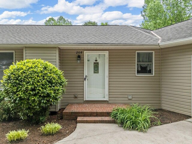 view of exterior entry featuring a shingled roof