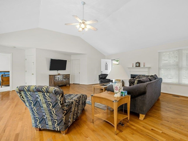 living room with lofted ceiling, a ceiling fan, plenty of natural light, and light wood-style flooring