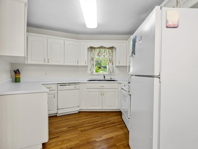 kitchen featuring white cabinetry, light wood-style flooring, a sink, and white appliances