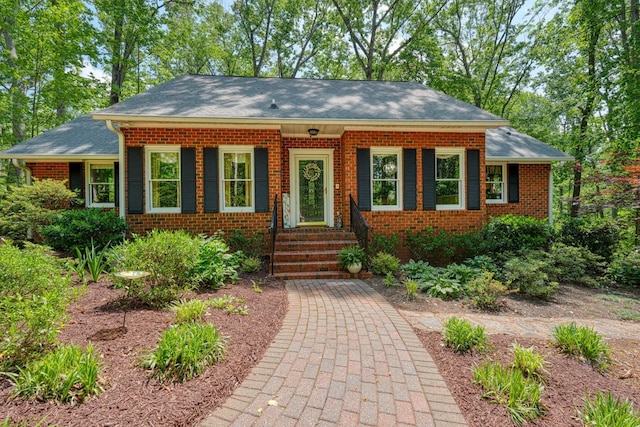 view of front of house with brick siding and roof with shingles