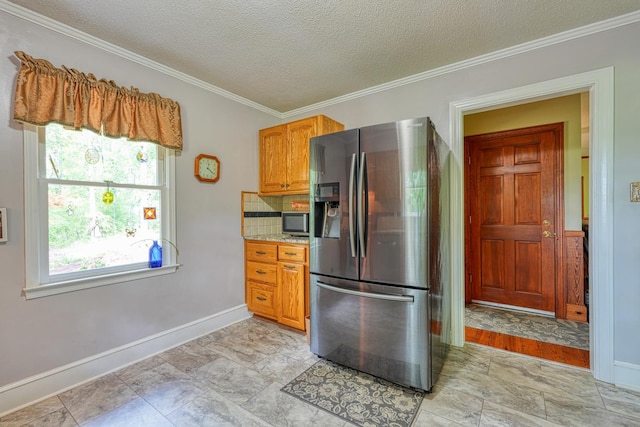 kitchen featuring a textured ceiling, stainless steel appliances, baseboards, and ornamental molding