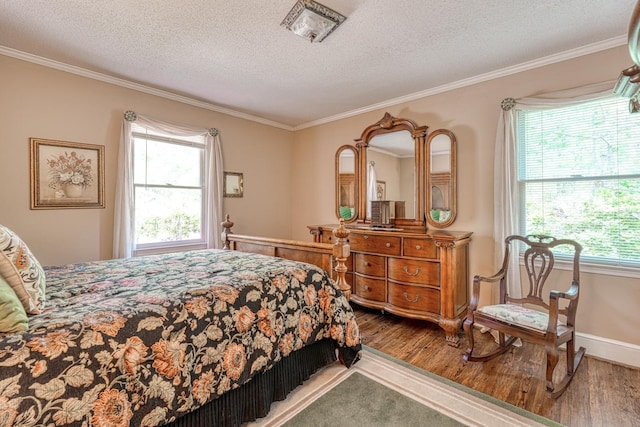 bedroom with a textured ceiling, wood finished floors, baseboards, and ornamental molding
