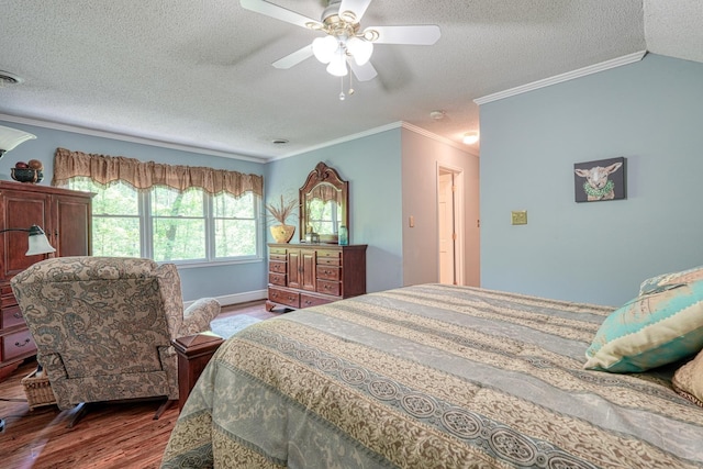 bedroom featuring wood finished floors, a textured ceiling, crown molding, a ceiling fan, and baseboards