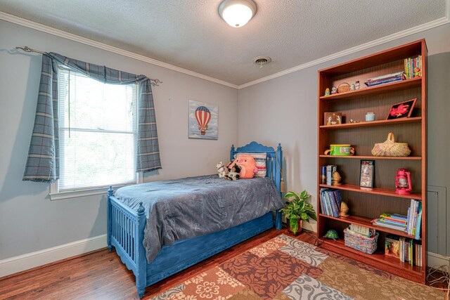 bedroom featuring crown molding, a textured ceiling, baseboards, and wood finished floors