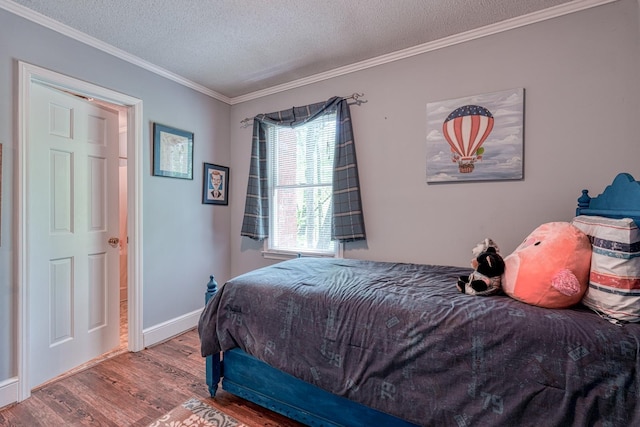bedroom with crown molding, a textured ceiling, baseboards, and wood finished floors