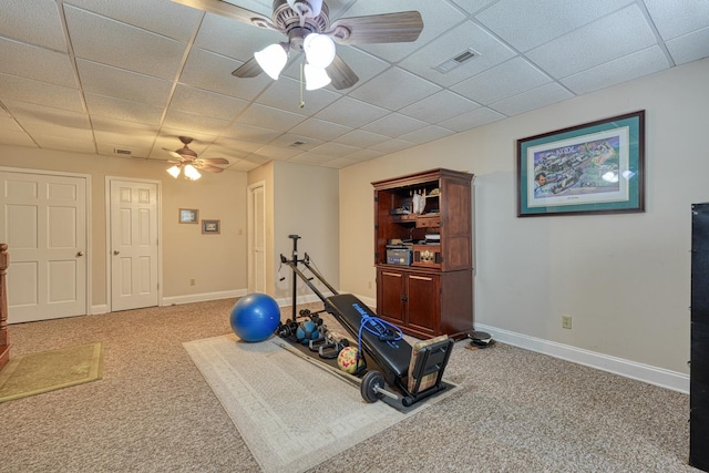 exercise area featuring a paneled ceiling, ceiling fan, and carpet flooring