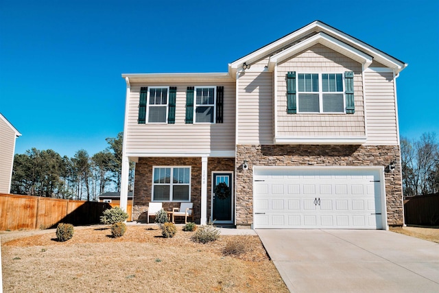 craftsman inspired home featuring concrete driveway, stone siding, and fence
